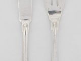 deux fourchettes et un couteau sur une surface blanche