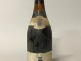 une vieille bouteille de vin posée sur une table blanche