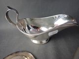 a silver gravy on a table next to a silver plate