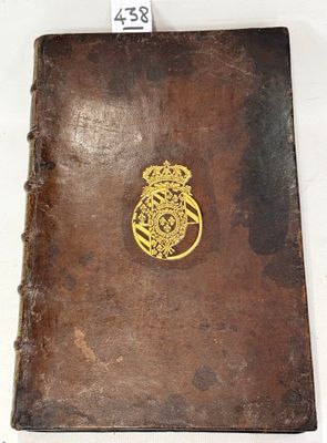 an old book with a gold emblem on it sitting on a table