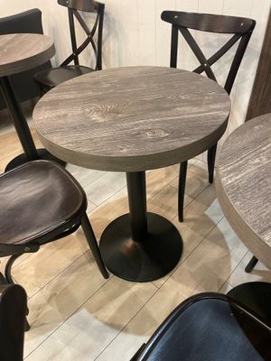 tables and chairs in a small room with wood floors and white walls