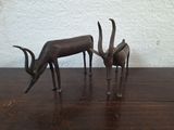 statue of two antelope standing next to each other on a wooden table