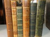 plusieurs vieux livres sont alignés sur une étagère dans une bibliothèque