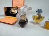 three perfume bottles and a box on a table with a bird figurine in it