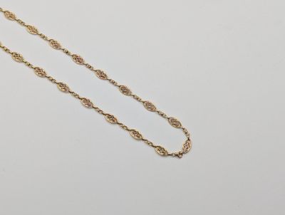 un collier à chaîne dorée avec un motif de nœud sur fond blanc
