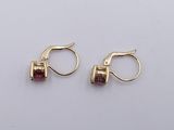 two pairs of gold and garnetite earrings on a white surface