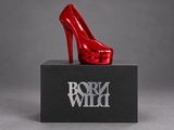 a close up of a red high heeled shoe on a black box