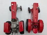 two red toy tractors sitting on a white surface