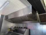 une cuisine équipée d'une plaque de cuisson en inox et d'une hotte aspirante