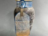 a glass jar with a label on it sitting on a wooden stand