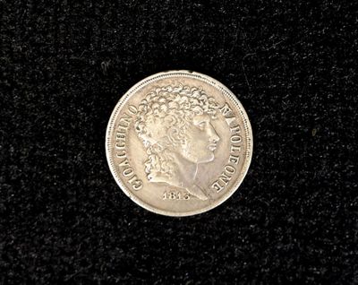 an old silver coin on a black surface with a black background