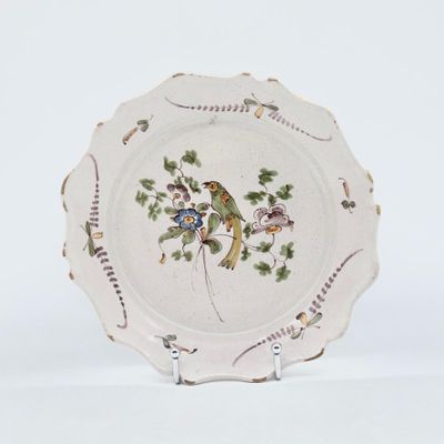 a white plate with a bird on it on a stand