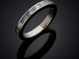 a close up of a wedding ring with diamonds on a black surface