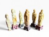 sept figurines de tailles et de formes différentes posées sur une surface blanche