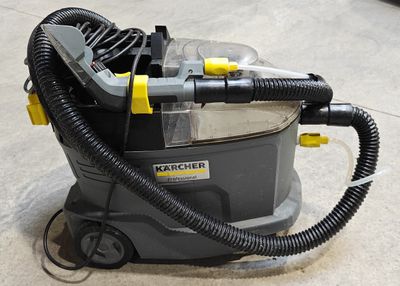 un aspirateur posé par terre, muni d'un tuyau