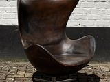 un fauteuil en cuir marron posé sur un trottoir en briques