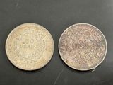 two coins, one silver and one silver, on a black surface