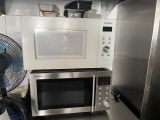 a microwave and a fan in a small kitchen