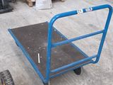 a blue cart with a yellow handle sitting on the ground