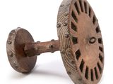 an old wooden wheel with holes on it sitting on a white surface