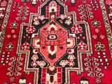 an oriental rug with a red and black design on a wooden floor