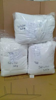 Plusieurs sacs contenant des oreillers blancs sont empilés sur une boîte en carton