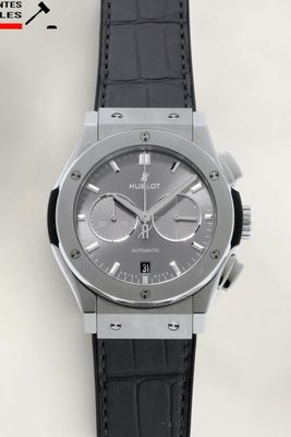 gros plan d'une montre sur une surface blanche avec un bracelet noir