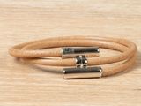 a close up of a pair of leather bracelets on a wooden surface