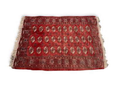 un vieux tapis rouge orné d'un motif en médaillon sur fond blanc
