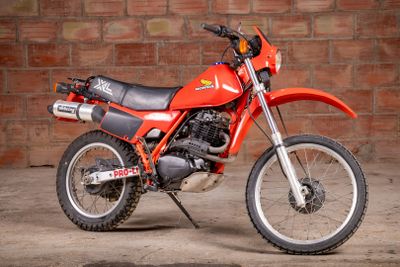 a red dirt bike parked in front of a brick wall