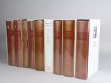 several books are lined up in a row on a white surface
