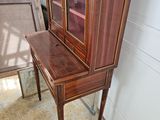 a wooden cabinet with a glass door and a chair in front of it