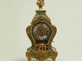 a green and gold clock sitting on a white surface