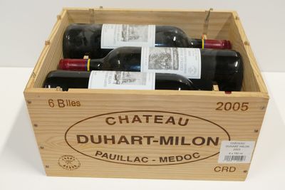 des bouteilles de vin rouge dans une caisse en bois posée sur une surface blanche