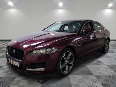 un Jaguar bordeaux garé dans une pièce au sol en damier