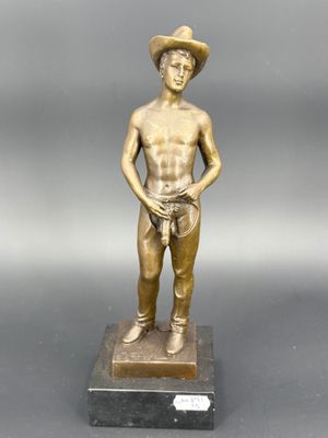 statue en bronze représentant un homme coiffé d'un chapeau et tenant un lasset