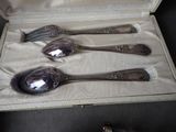 three silver spoons and a fork in a case