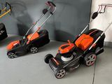 three lawn mowers are lined up against a wall in a garage