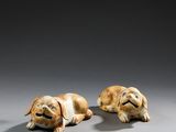 deux petites figurines représentant des chiens couchés sur une surface grise