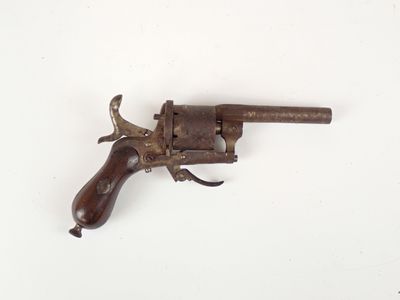 un vieux revolver avec une poignée en bois sur une surface blanche