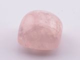 un gros plan d'un caillou rose sur une surface blanche