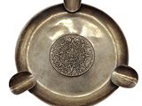 une assiette en argent ornée d'un motif sur fond blanc