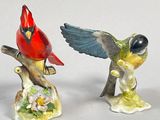 two figurines of birds that are sitting on a tree branch
