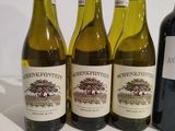 four bottles of wine are lined up on a white surface