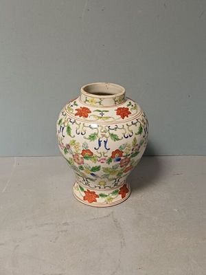 a white vase with flowers on it sitting on a table