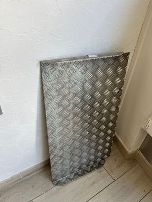 a metal basket that is sitting on the floor next to a wall