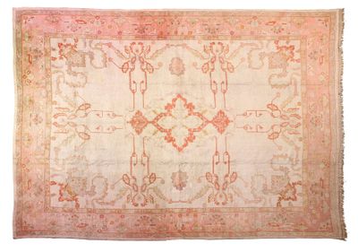 un tapis ancien orné d'un motif rose et beige sur fond blanc