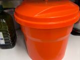 an orange bucket sitting on a shelf in a kitchen