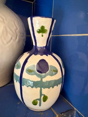 un vase posé sur une étagère à côté d'un autre vase