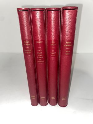 quatre livres rouges sont alignés les uns à côté des autres sur une surface blanche